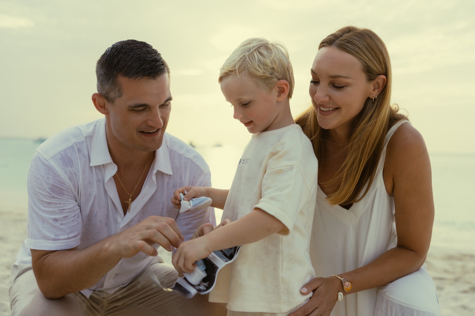 Jon and Jaclyn helping their son hold tiny baby shoes and an ultrasound