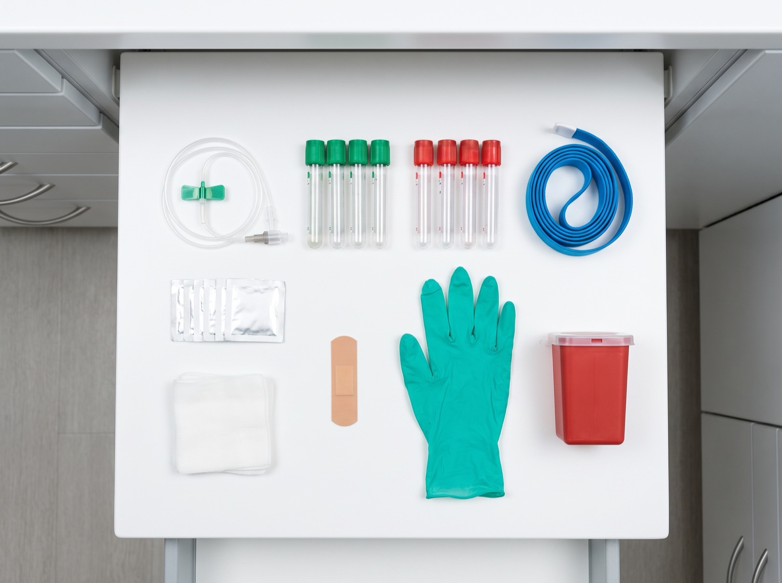 PRF draw station — butterfly needle, PRF tubes, tourniquet, gauze, gloves and sharps container laid out in a drawer